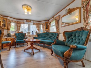 Ein Zimmer mit Holzboden, einem runden Holztisch und vier stuhlartigen Sitzgelegenheiten in Türkis mit Holzbeinen.