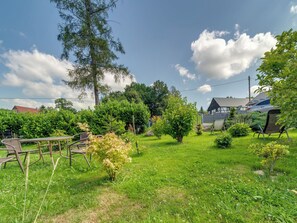 A grassy outdoor area with a picnic table, a small tree, and a house in the background. - Superior by Interhome (Leśna)