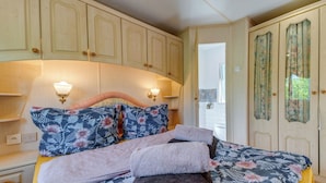 A bedroom with a bed, two wall-mounted lamps, a nightstand, a dresser, and a door with a mirror. - Superior by Interhome (Leśna)