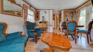 A room with a wooden dining table, blue upholstered chairs, a mirror, and a cabinet. - Superior by Interhome (Leśna)
