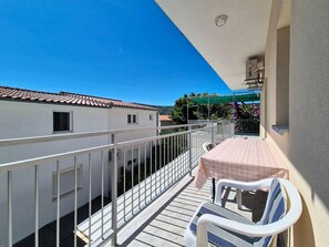 Ein Balkon mit Tisch und Stühlen, einer Brüstung und Blick auf umliegende Gebäude.