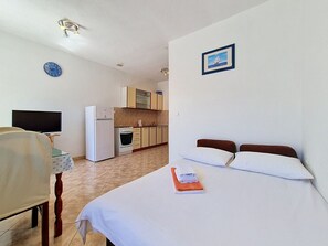 A hotel room with a bed, a desk, a chair, a refrigerator, a microwave, and a small kitchenette. - Vukelja by Interhome (Marina)