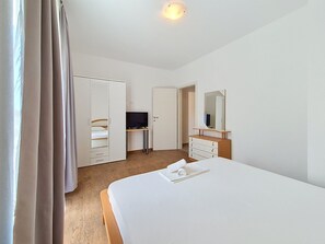 Een hotelkamer met een bed, een televisie, een kledingkast en een spiegel.