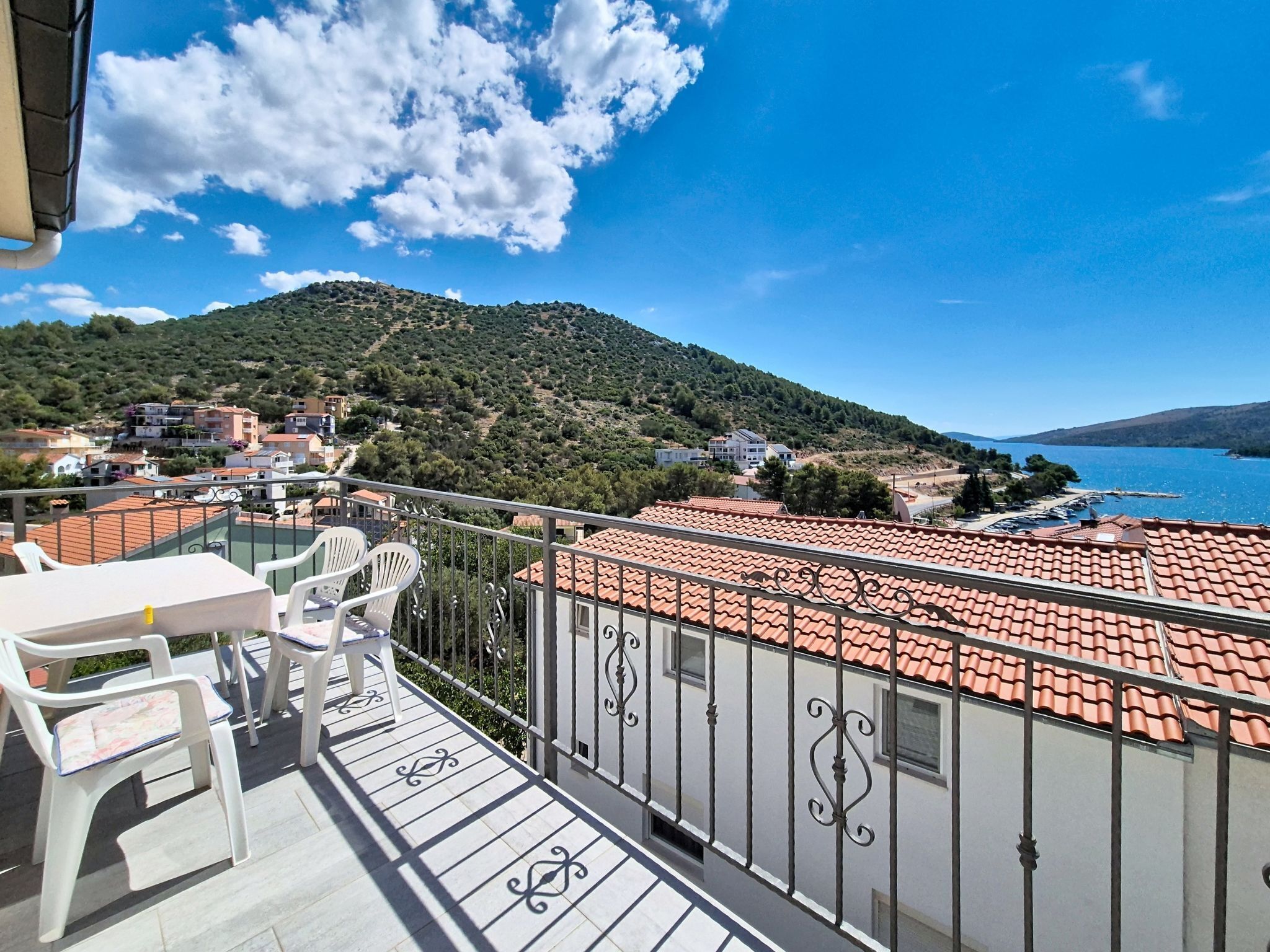 Un balcon donnant sur une colline et un plan d’eau.
