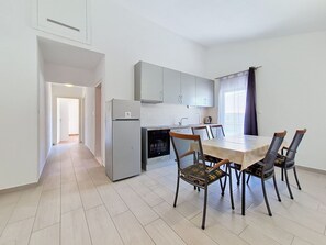 A modern kitchen with white cabinets, a built-in oven, and a dining area with a table and chairs. - Vukelja by Interhome (Marina)
