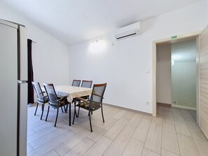 A room with a dining table, chairs, an air conditioning unit, and a door marked 'EXIT'. - Vukelja by Interhome (Marina)