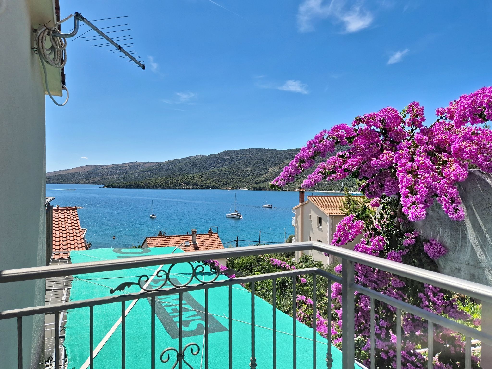 A balcony with a view of a body of water, boats, and a mountainous landscape.