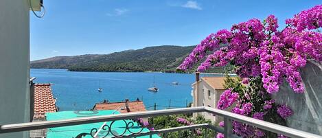 A balcony with a view of a body of water, boats, and a mountainous landscape.