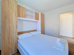A single bed with white bedding, a wooden headboard, and a wooden wardrobe above it. - Vukelja by Interhome (Marina)