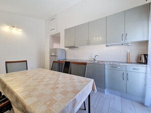 A compact kitchen with grey cabinets, a sink, and a dining table with chairs. - Vukelja by Interhome (Marina)