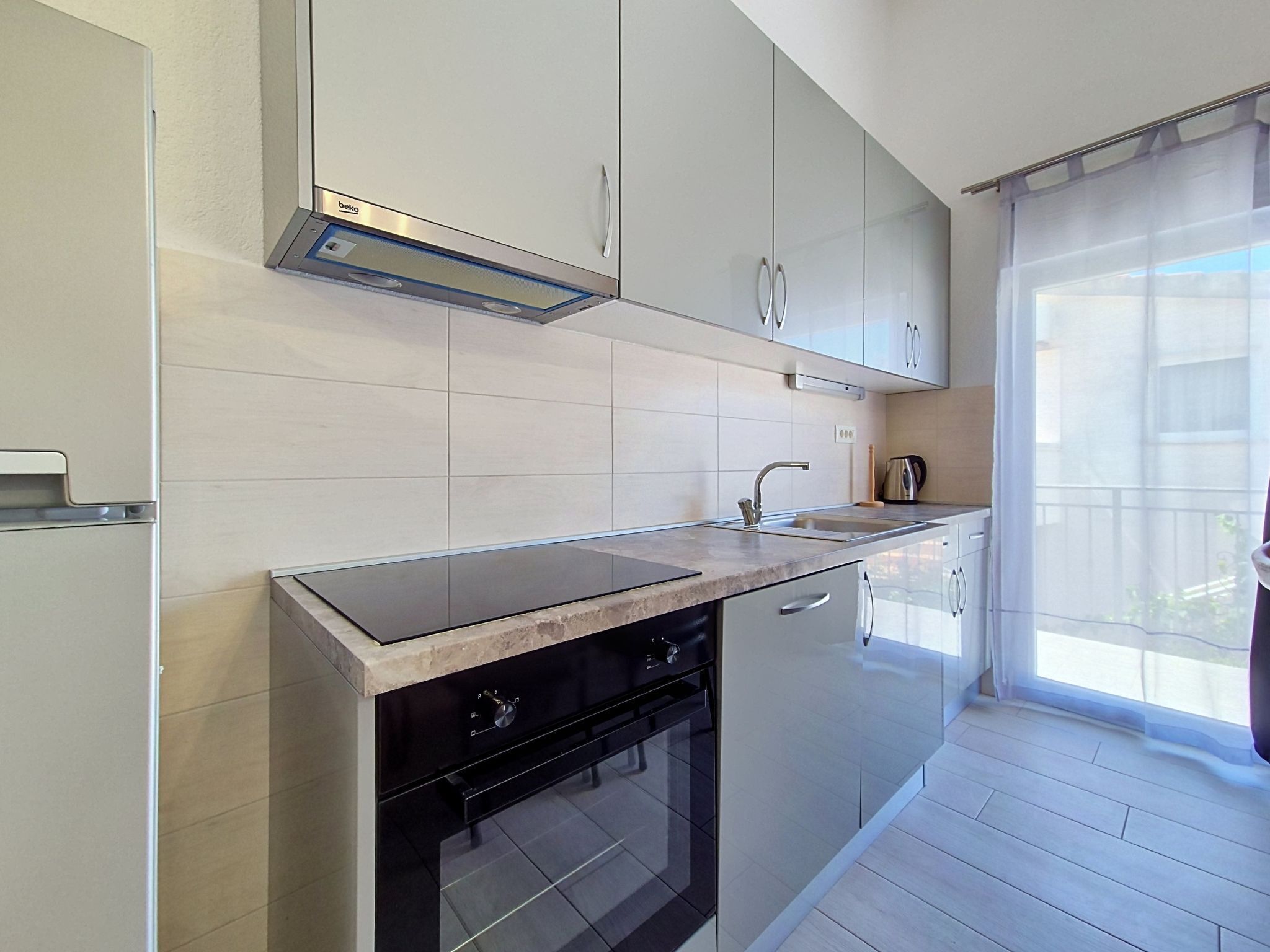 Una cocina moderna con horno empotrado, gabinetes de acero inoxidable y un ventanal que aporta luz natural.