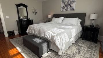 A bedroom with a bed, a ceiling fan, a nightstand, a dresser, a bench, and a rug.