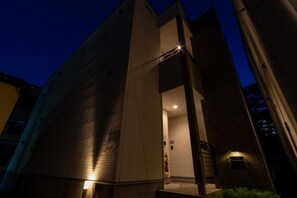 A modern building with a prominent entrance, a visible fire extinguisher, and a well-lit interior. - Florence M's Hakata (Fukuoka City Hakataku  Katakasu)