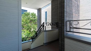 A modern building with a staircase, a view of greenery, and a brick wall.