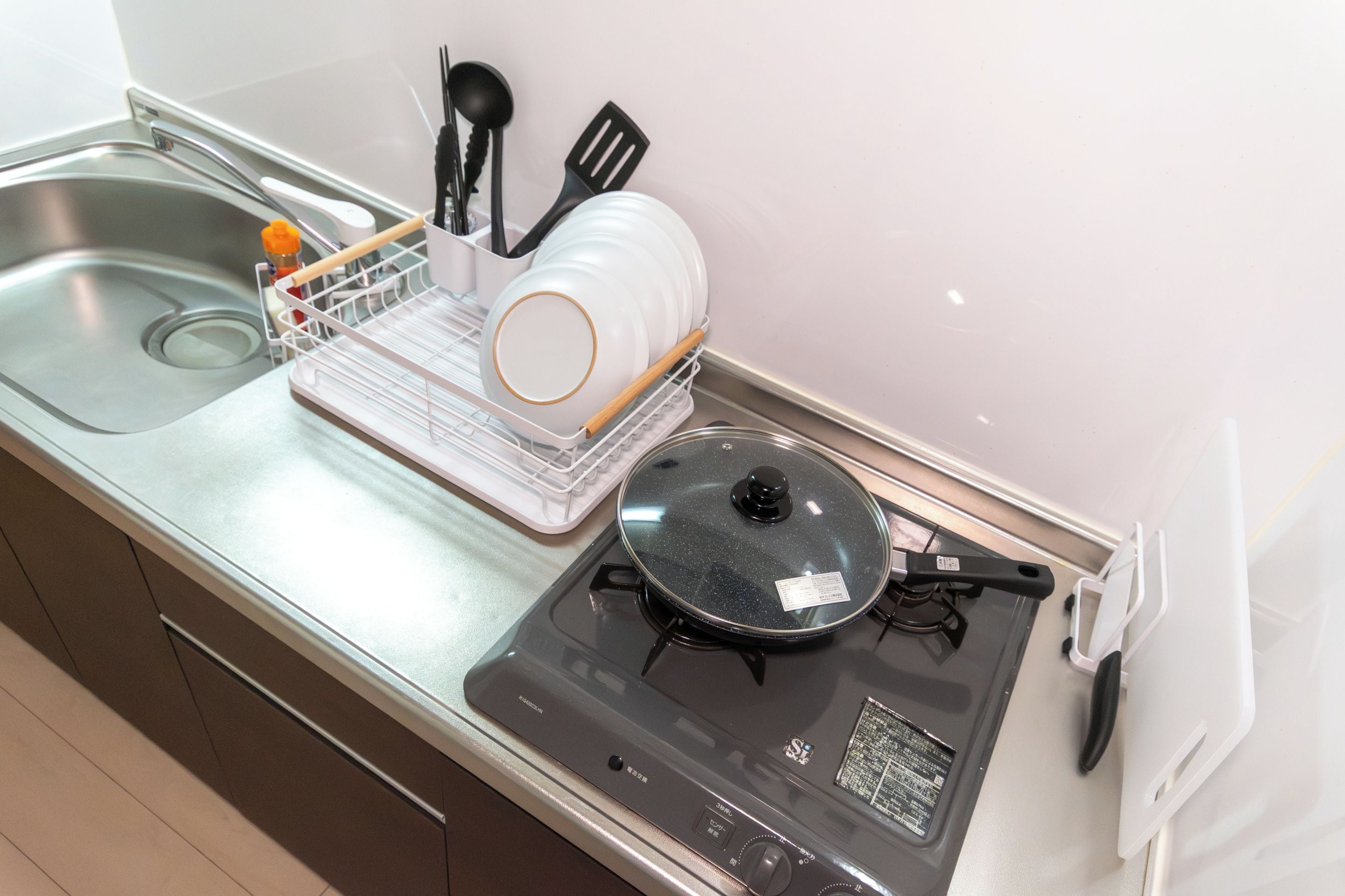 A kitchen with a stove, sink, and dish rack.