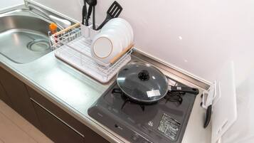 A kitchen with a stove, sink, and dish rack.