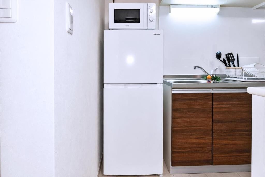 Una cocina compacta con un refrigerador blanco, un microondas y un mueble de madera.