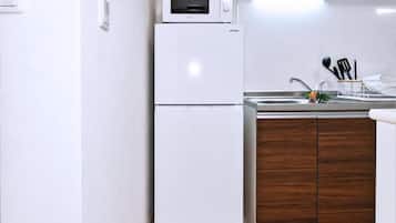 Una cocina compacta con un refrigerador blanco, un microondas y un mueble de madera.