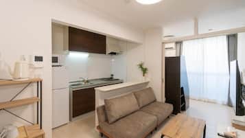 A compact living space with a kitchenette, a sofa, a dining table, and a TV.