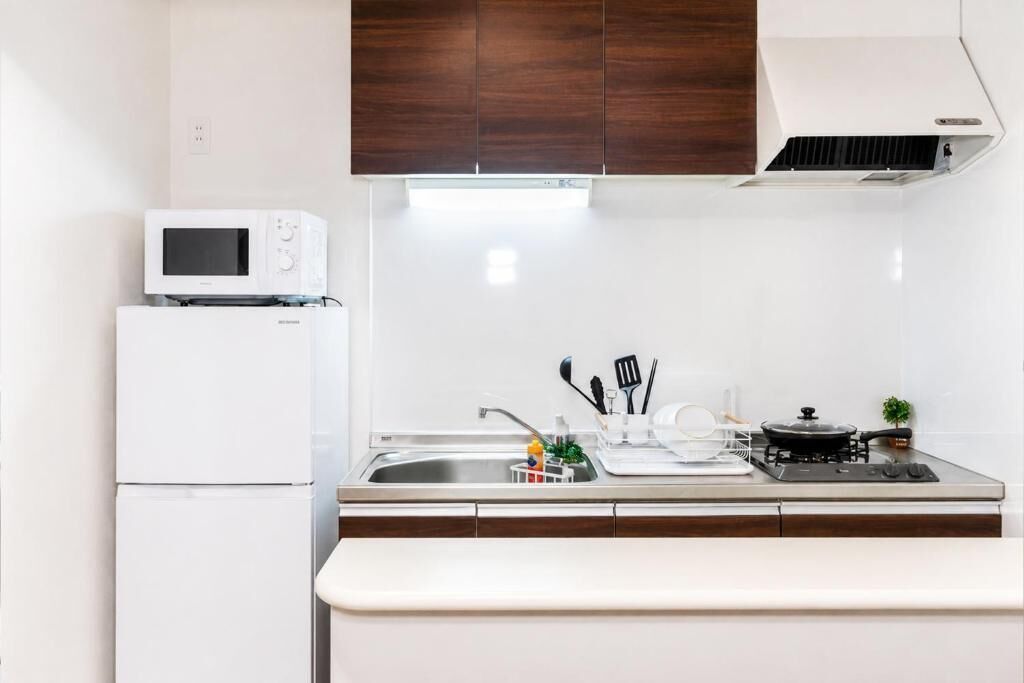 A compact kitchen with a microwave, stove, sink, and wooden cabinets.