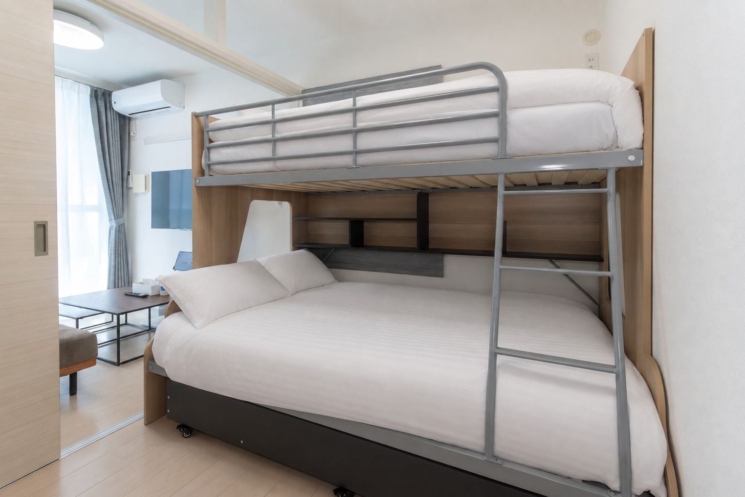 Una cama litera con escritorio y silla, una lámpara y una ventana con cortinas.