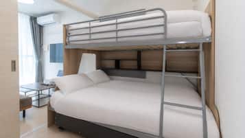 Una cama litera con escritorio y silla, una lámpara y una ventana con cortinas.