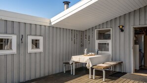 Un espacio de descanso al aire libre con techo, una mesa, sillas, una chimenea y una ventana.