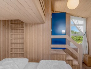 Ein Holzblockhaus-Interieur mit einem Bett, einer blauen Tür und einer Treppe.