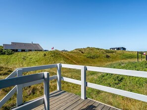 Una terraza de madera que conduce a un área verde con casas al fondo.
