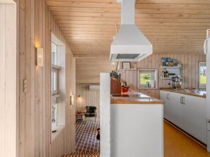 A modern kitchen with wooden walls, a central island, and a view of the outdoors. - "Elsamaria" - 400m from the sea by Interhome (Blokhus)