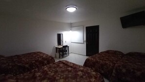 A room with two beds, a desk, a chair, a TV, and a door. - Hotel Flores Hills (Monclova)