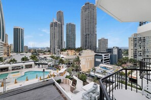 A high-rise hotel with a rooftop pool, multiple balconies, and a view of surrounding high-rise buildings. - Cozy 2 Double-bed Hotel Room | Max 4 guests (Surfers Paradise)