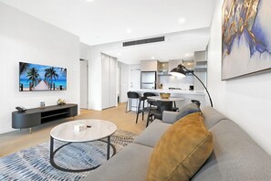 A modern living room with a sofa, coffee table, and artwork on the wall. - Casino-Side 2BR Ocean View | Walk to Beach/Tram (Broadbeach)