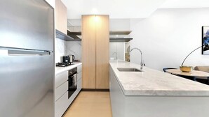 A modern kitchen with a built-in oven, a sink, and a coffee machine. - Casino-Side 2BR Ocean View | Walk to Beach/Tram (Broadbeach)