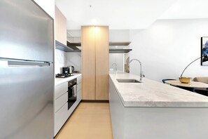 A modern kitchen with a built-in oven, a sink, and a coffee machine. - Casino-Side 2BR Ocean View | Walk to Beach/Tram (Broadbeach)