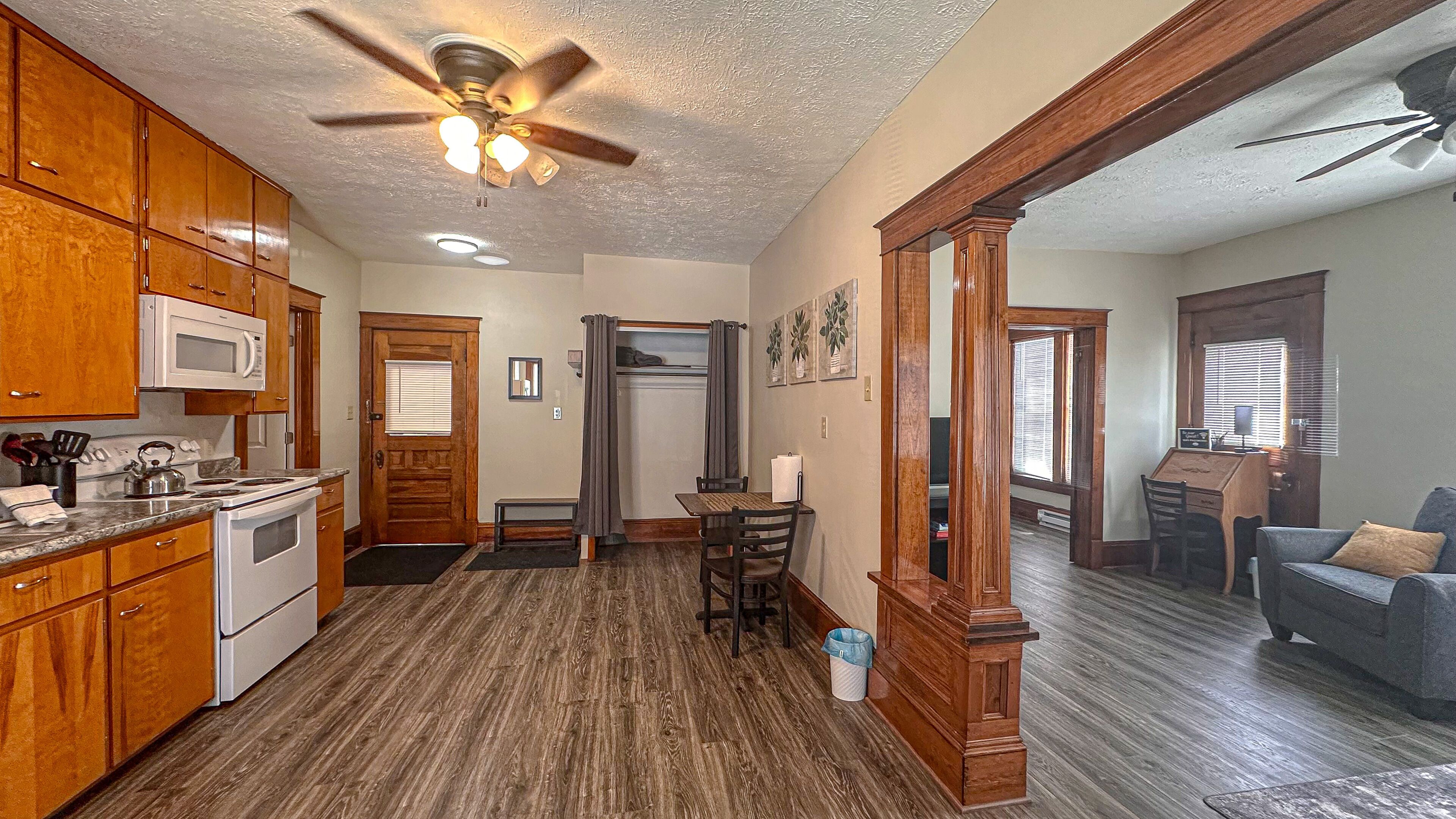 A kitchen with wooden cabinets, a microwave, and a ceiling fan.