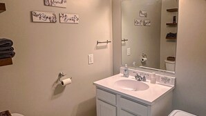 Ein Badezimmer mit Toilette, Waschbecken, Spiegel und Mülleimer.