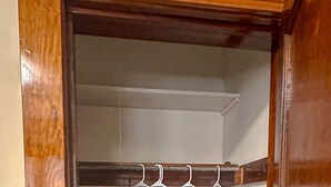 Ein begehbarer Kleiderschrank mit Holzeinrahmung, einem Metallgestell und weißen Kleiderbügeln.