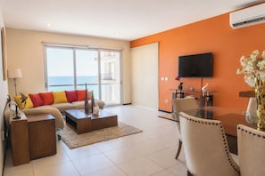 A modern living room with a sofa, coffee table, and dining table. - Family 3-Bedroom Oceanfront on the Malecón (Mazatlán)