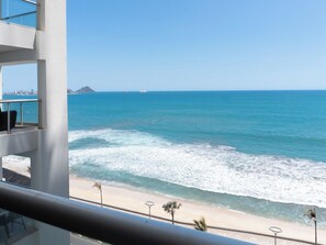 A balcony with a view of the ocean, beach, and distant cityscape. - Family 3-Bedroom Oceanfront on the Malecón (Mazatlán)