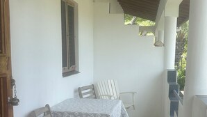 Un espacio al aire libre techado con una mesa, sillas, una ventana y baldosas de suelo con diseño.
