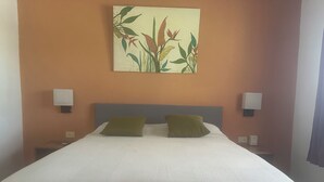 Habitación de hotel con cama, dos almohadas, una obra de arte colgada en la pared y lámparas de noche.