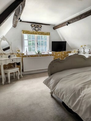 A bedroom with a bed, a dresser, a vanity with a mirror, a television, and a window with curtains. - 2BR Cottage for up to 2 adults, 2 children and dogs (Wiltshire)