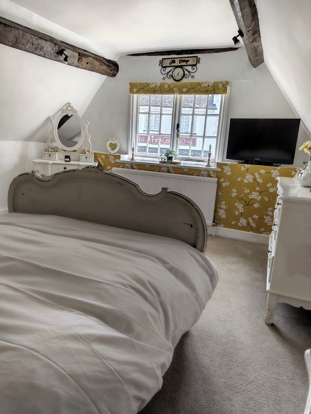 Een slaapkamer met een bed, een dressoir, een televisie, een raam met uitzicht en een decoratief wandobject.