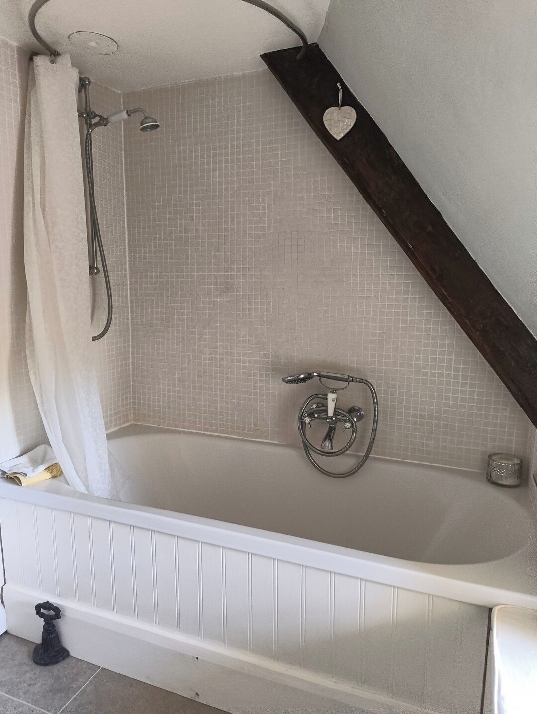 A bathroom with a bathtub, a shower, and a towel rack.