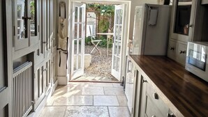 Uma cozinha com portas abertas para um jardim, piso de pedra e armários de madeira.