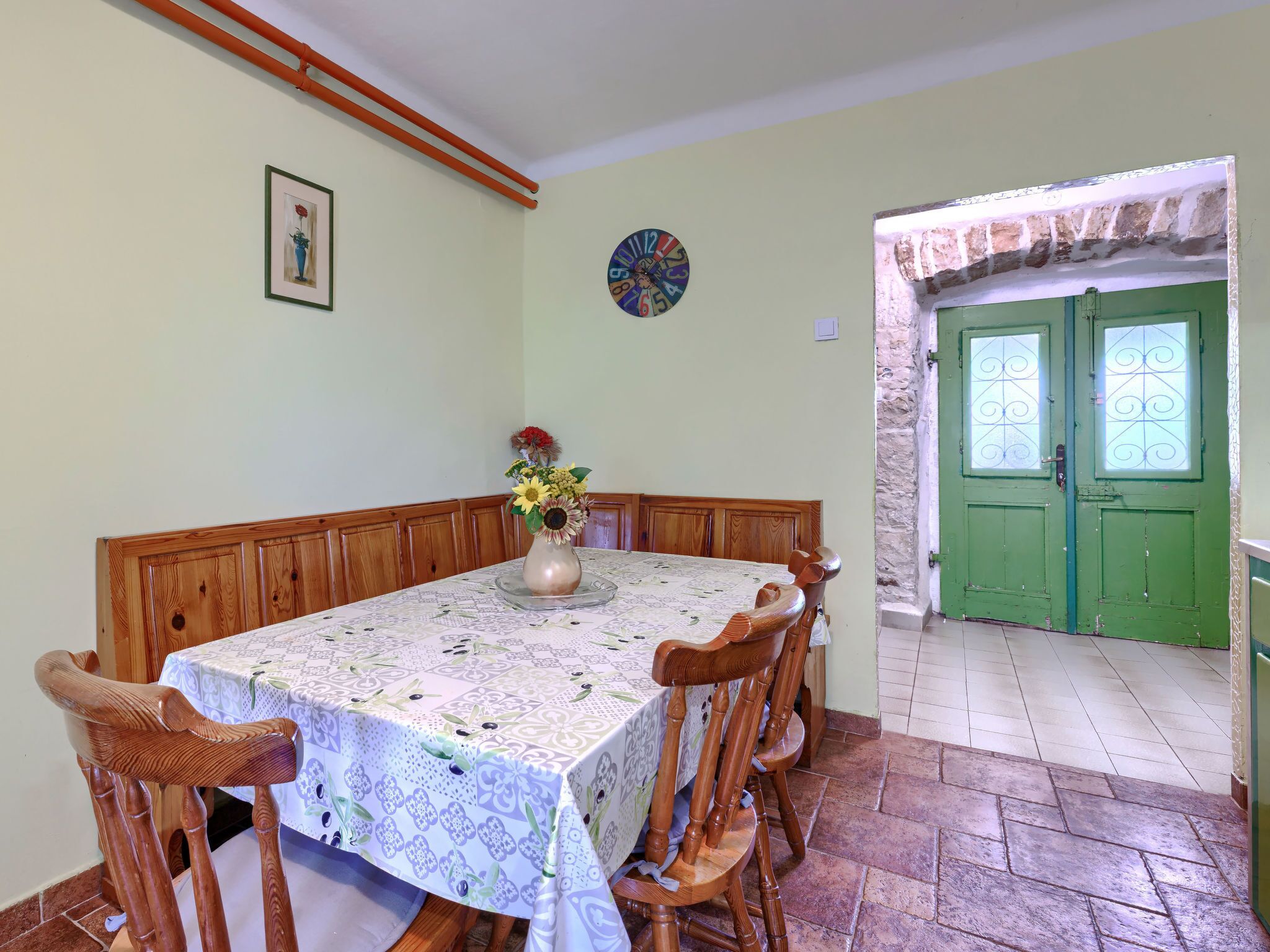 Un coin repas avec une table dressée pour six personnes, entourée de chaises en bois.