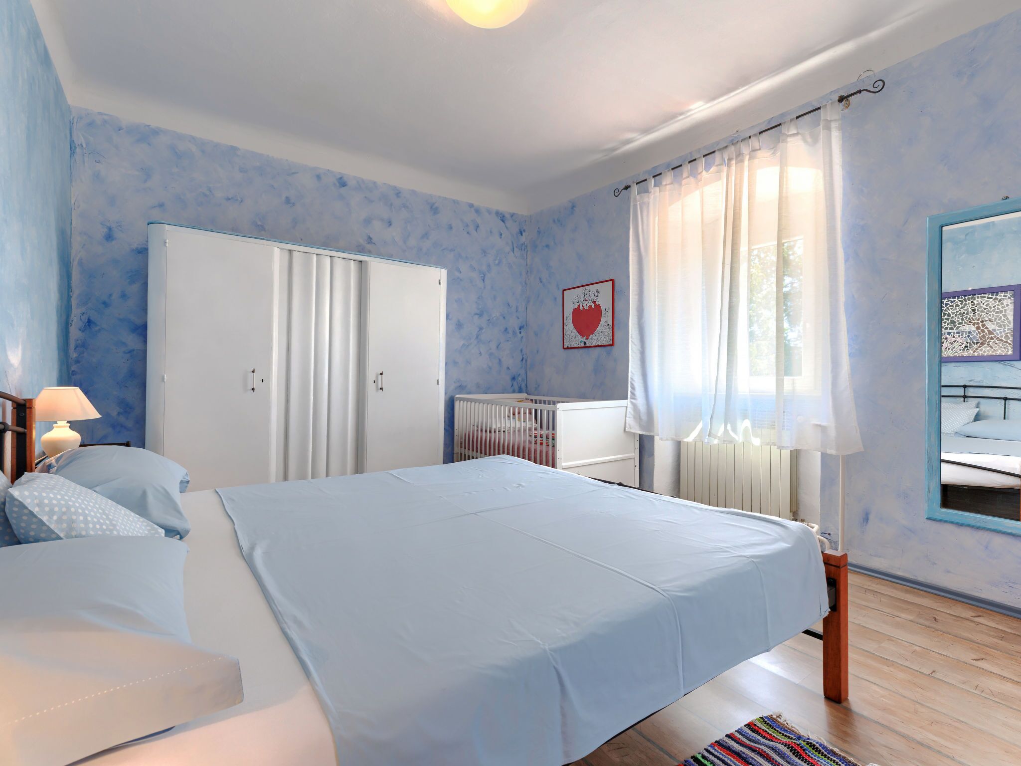 A bedroom with a bed, wardrobe, and a window with curtains.