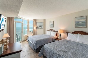 A hotel room with two beds, a balcony with a view of the sea, and a sign for Big Fish Rentals. - 2BR Oceanfront View at Carolinian with Amazing  Pool (Myrtle Beach)