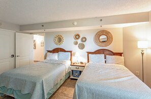A hotel room with two beds, a bedside table with a lamp, and decorative wall art. - 2BR Oceanfront View at Carolinian with Amazing  Pool (Myrtle Beach)
